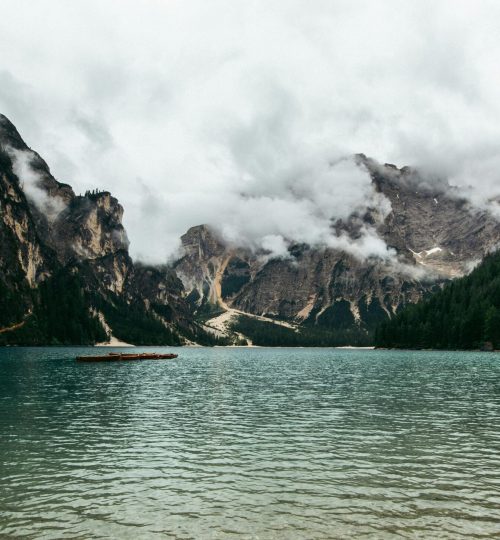 A serene view of a foggy mountain range reflected in a calm lake, offering a peaceful landscape.