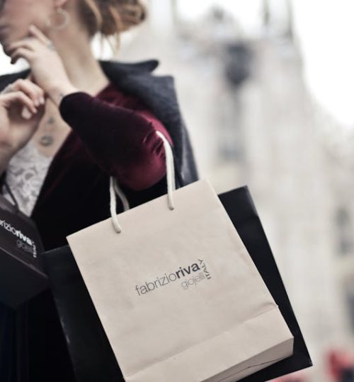 Stylish woman holding designer shopping bags near Milan's iconic Duomo. Urban fashion and lifestyle concept.